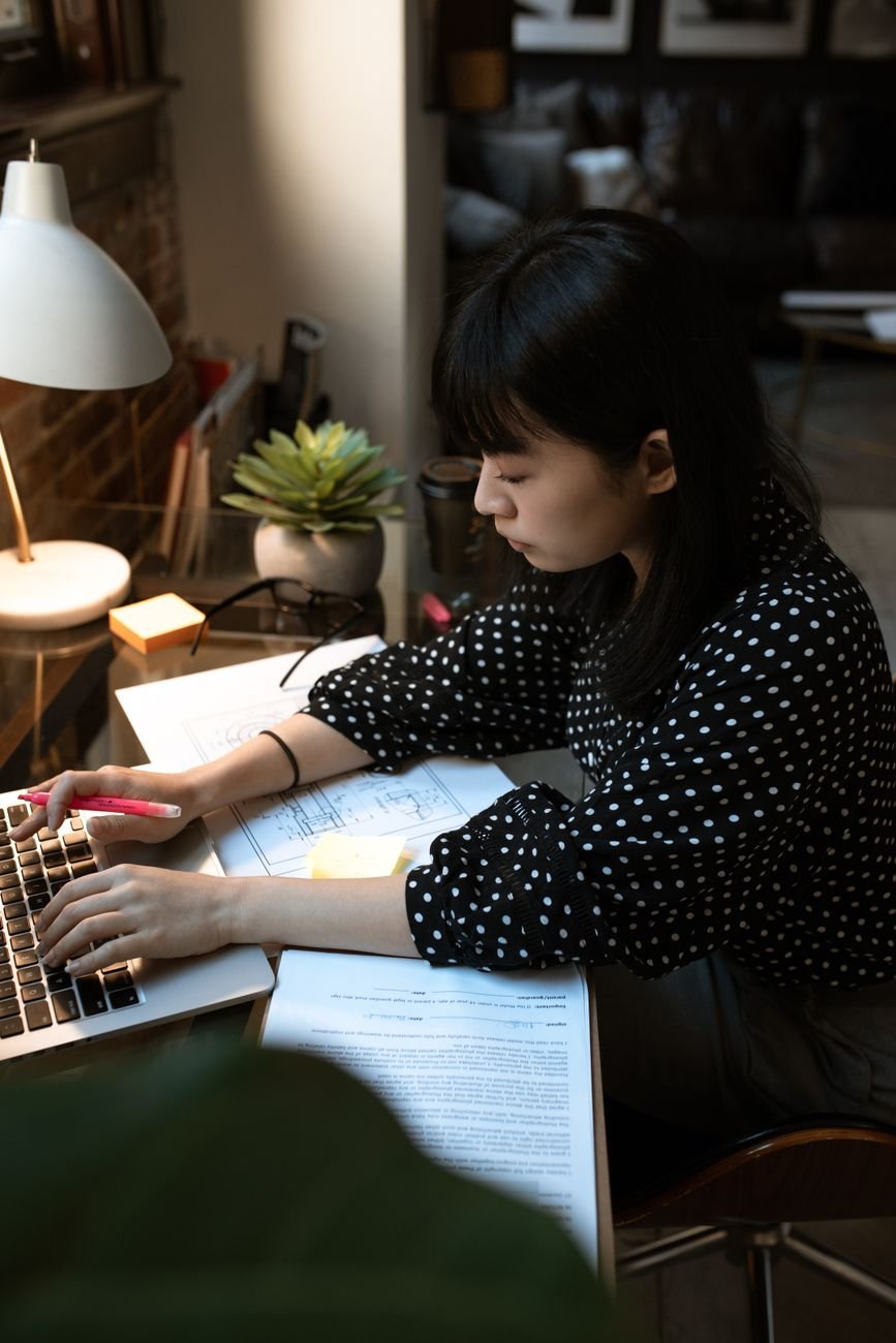 Focused woman working at a desk in a stylish home office with warm lighting.
